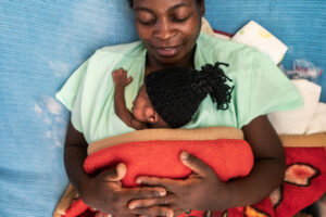 A woman holds a newborn in the kangaroo mother care position.