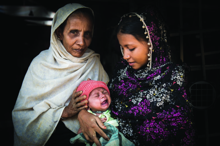 Two women hold a crying baby.